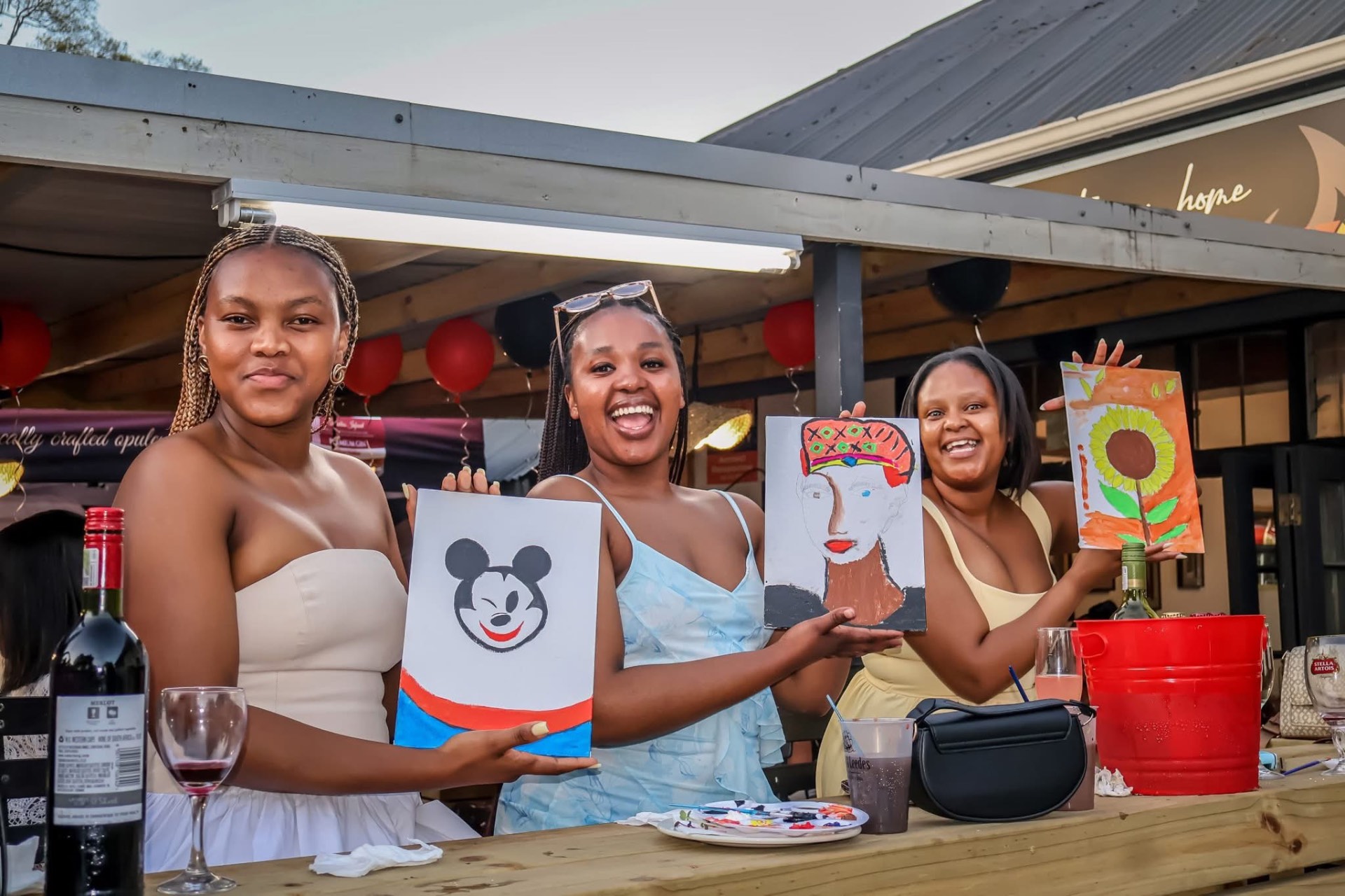 Guests showing off their paintings at a sip-and-paint evening