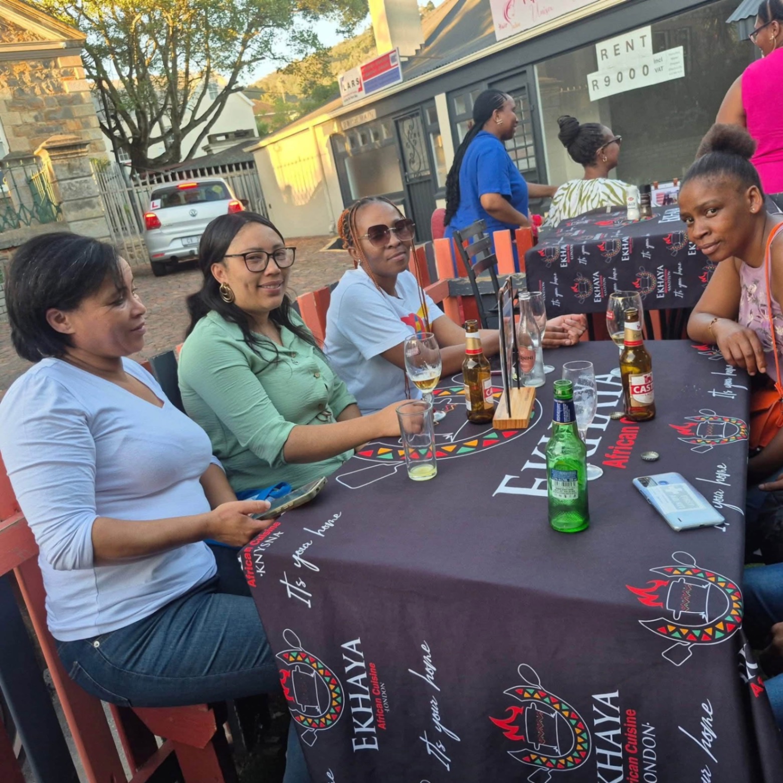 Friends catching up over drinks at an outdoor Ekhaya table