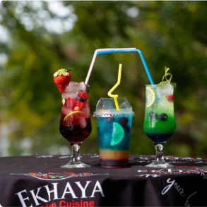 Three vibrant Ekhaya cocktails on a branded table