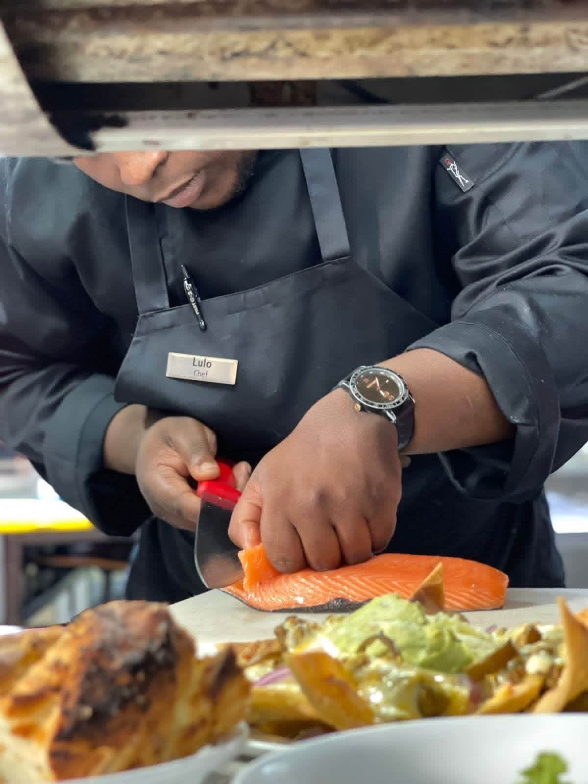 Chef Sikhululo Lulo Mhlaba holding a cast iron potjie pot in the Ekhaya kitchen