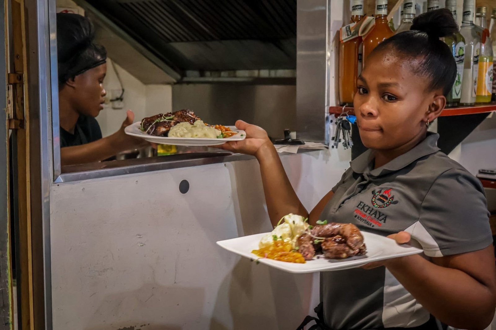 Hands serving a steaming bowl of traditional stew onto a wooden board
